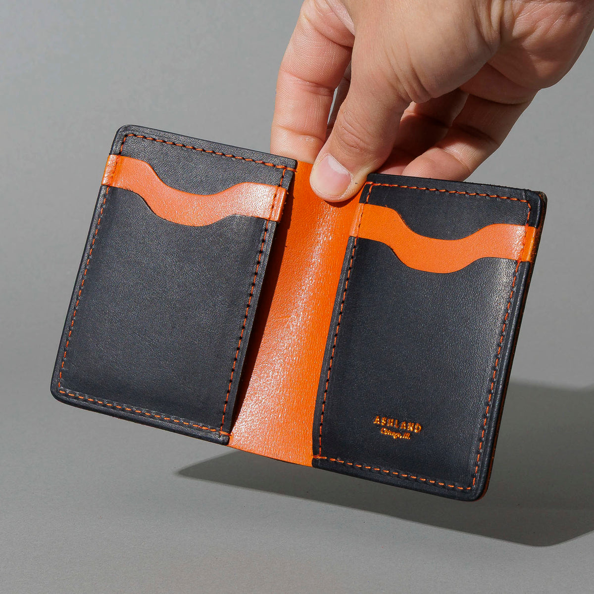 Tall Vertical Tony in Black Dublin with Orange Accents, held open in hand, shot 1