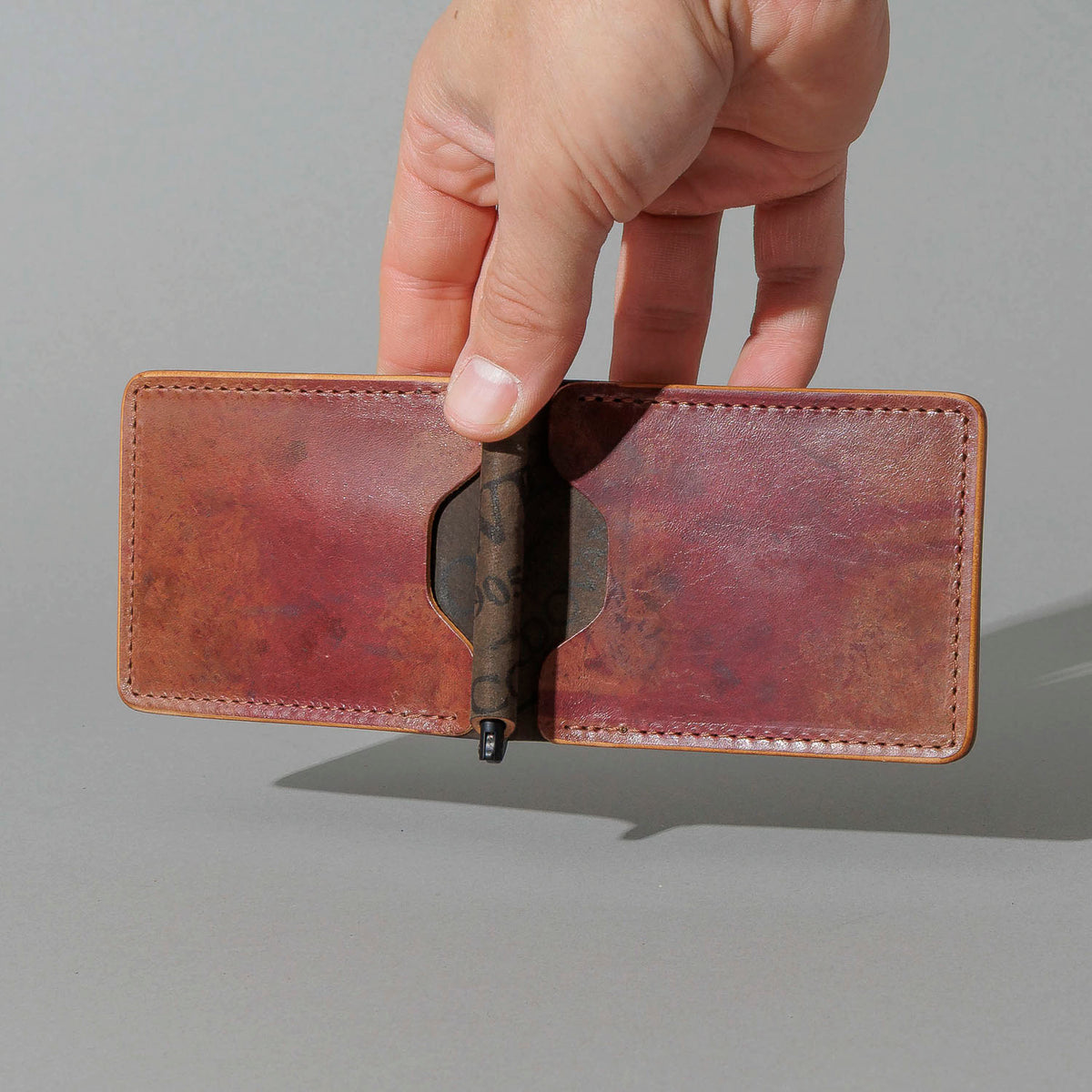 One-Off Capone Money Clip in Hand-Glazed Reverse Shell Cordovan, held open in hand, shot 2