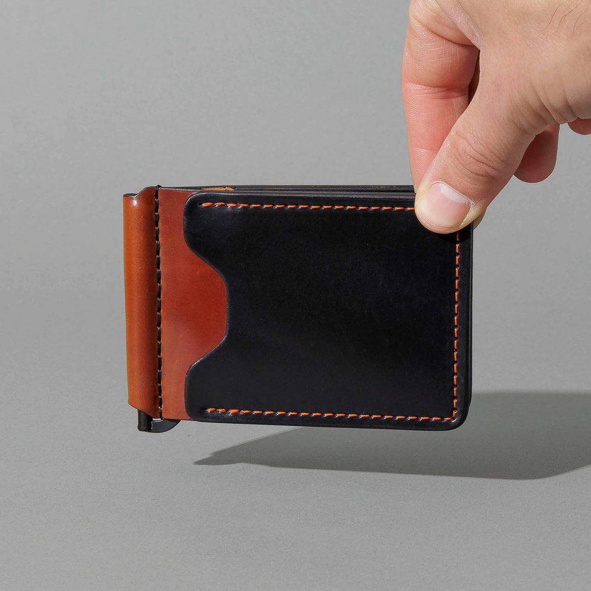 One-Off Capone Money Clip in Black on Blood Orange Shell Cordovan, held in hand