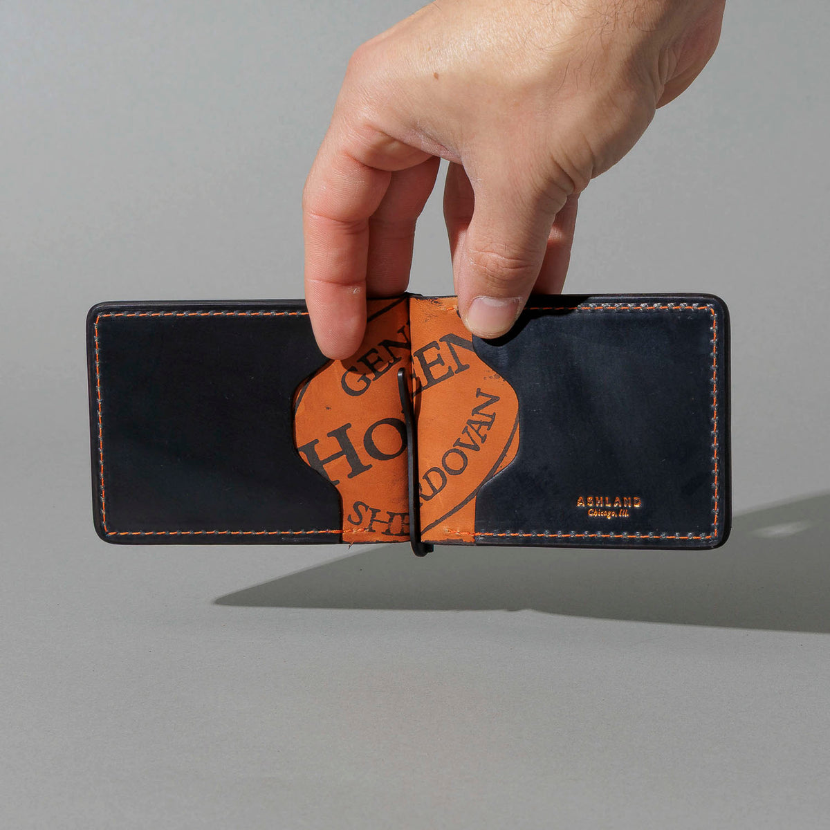 One-Off Capone Money Clip in Black on Blood Orange Shell Cordovan, held open in hand, shot 1