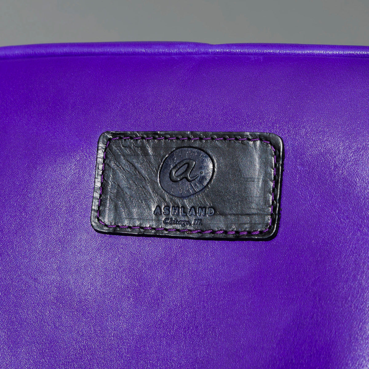 One-Off Sling Bag in Violet Latigo, close-up of the logo patch