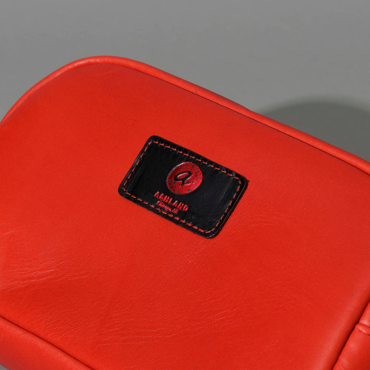 One-Off Sling Bag in Red Latigo, close-up of the logo patch