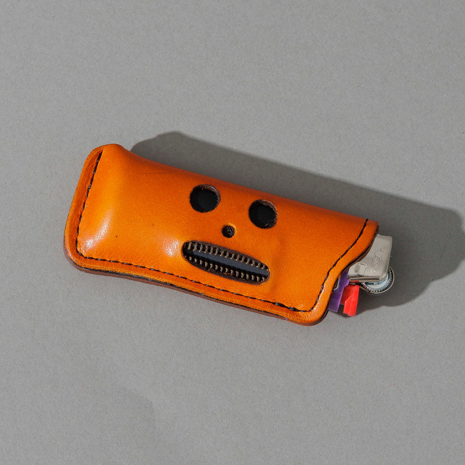 One-Off Skeleton Lighter in Orange Latigo, skeleton face design, front view, shot 2