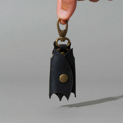Bat Leather Key Case in Black Dublin, hanging from fingers by the clip, shot 1