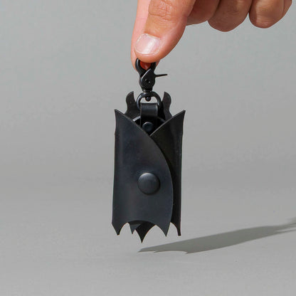Bat Leather Key Case in Blacked Out Black Shell Cordovan, hanging from fingers by the clip, shot 1