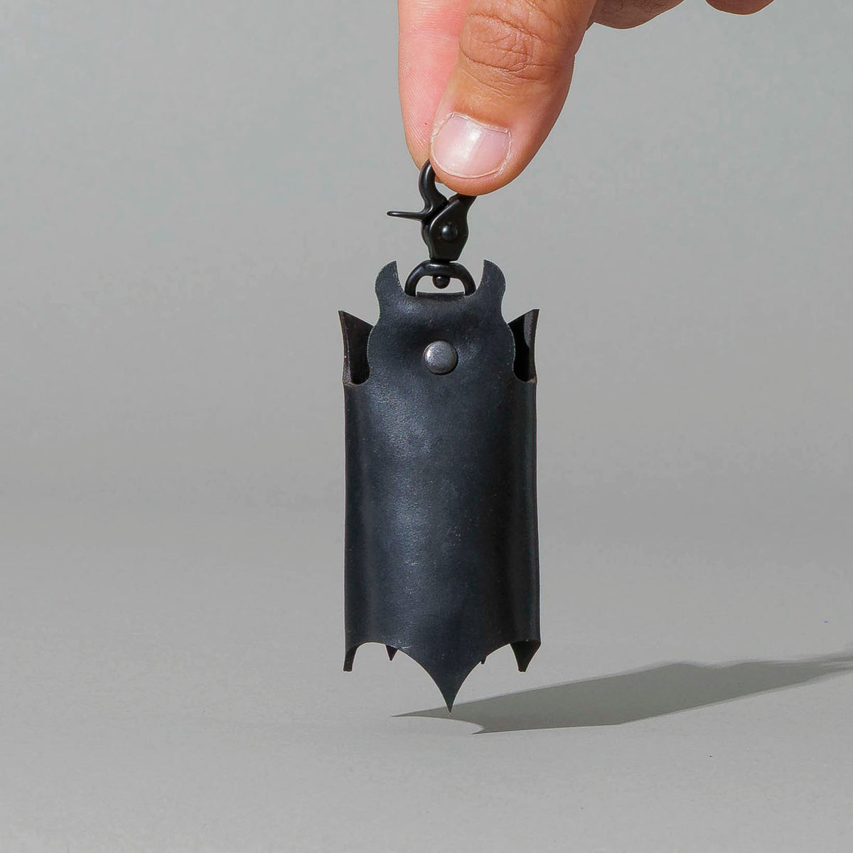 Bat Leather Key Case in Blacked Out Black Shell Cordovan, hanging from fingers by the clip, shot 2