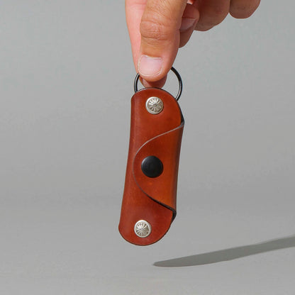 Vault Key Holder in Blood Orange Shell Cordovan, hanging from fingers by the clip, shot 2