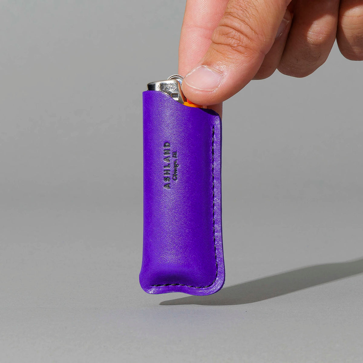 Lighter in Violet Latigo, BIC lighter in sheath, held in hand