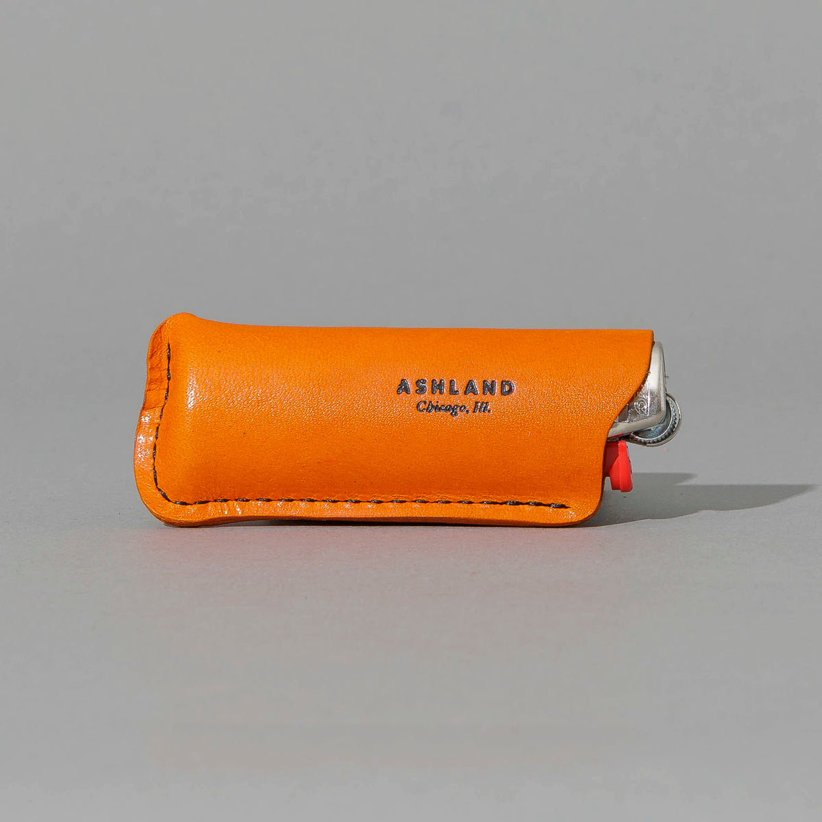 Lighter in Orange Latigo, angled view lying flat, shot 1