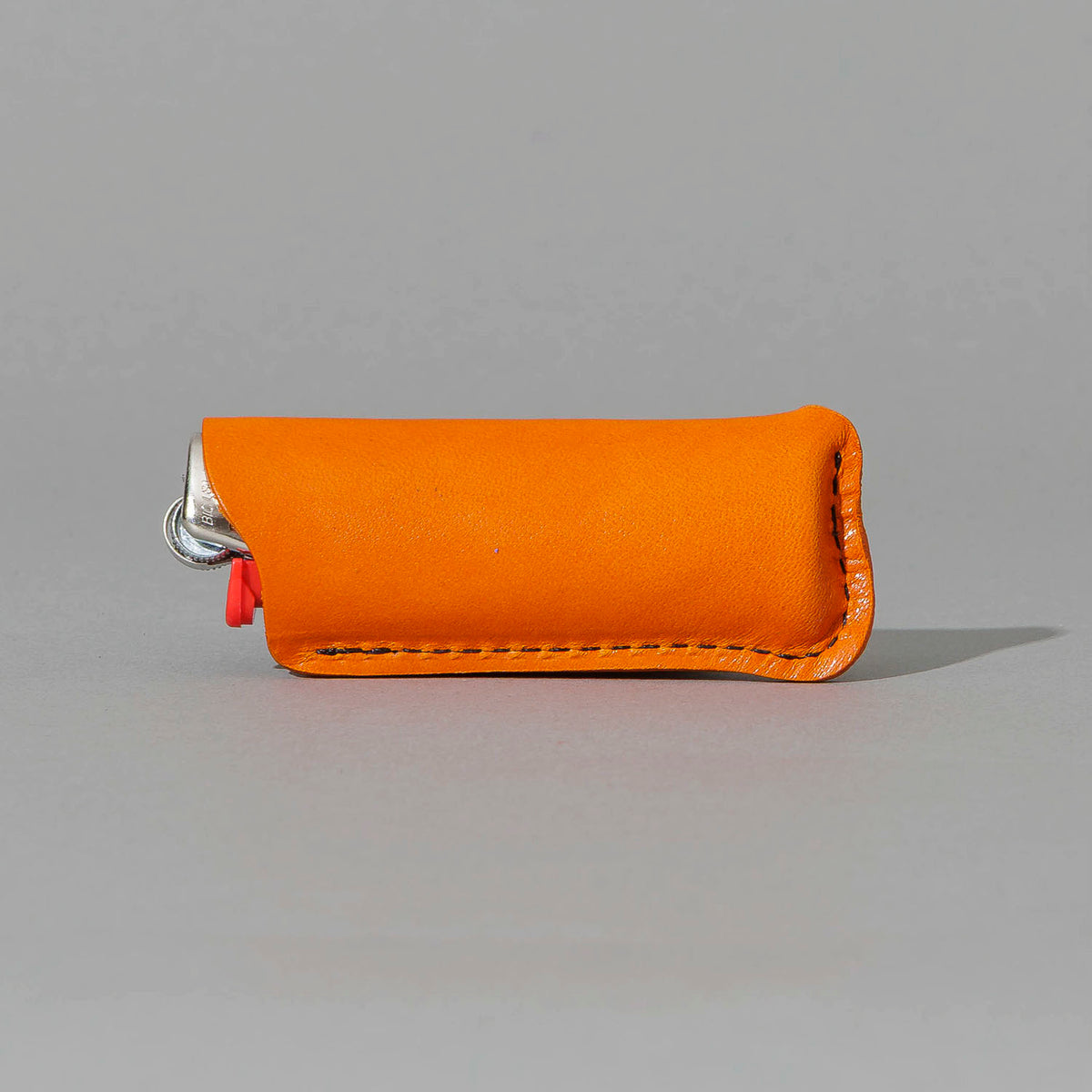 Lighter in Orange Latigo, angled view lying flat, shot 2