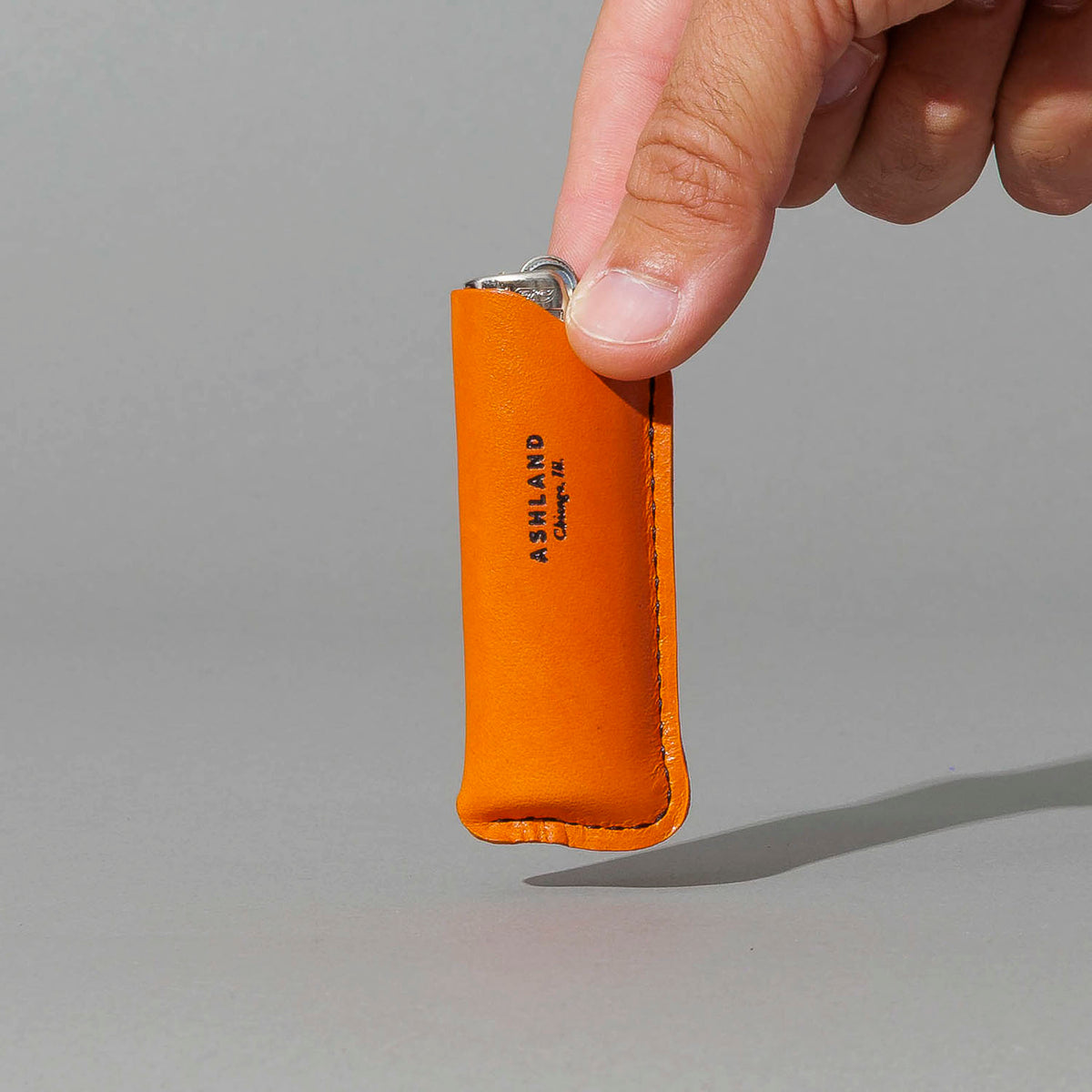 Lighter in Orange Latigo, BIC lighter in sheath, held in hand