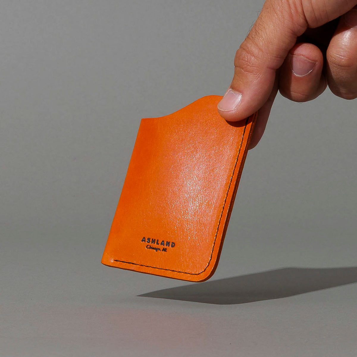 One-Shot Card Case in Orange Latigo, held in hand, shot 3