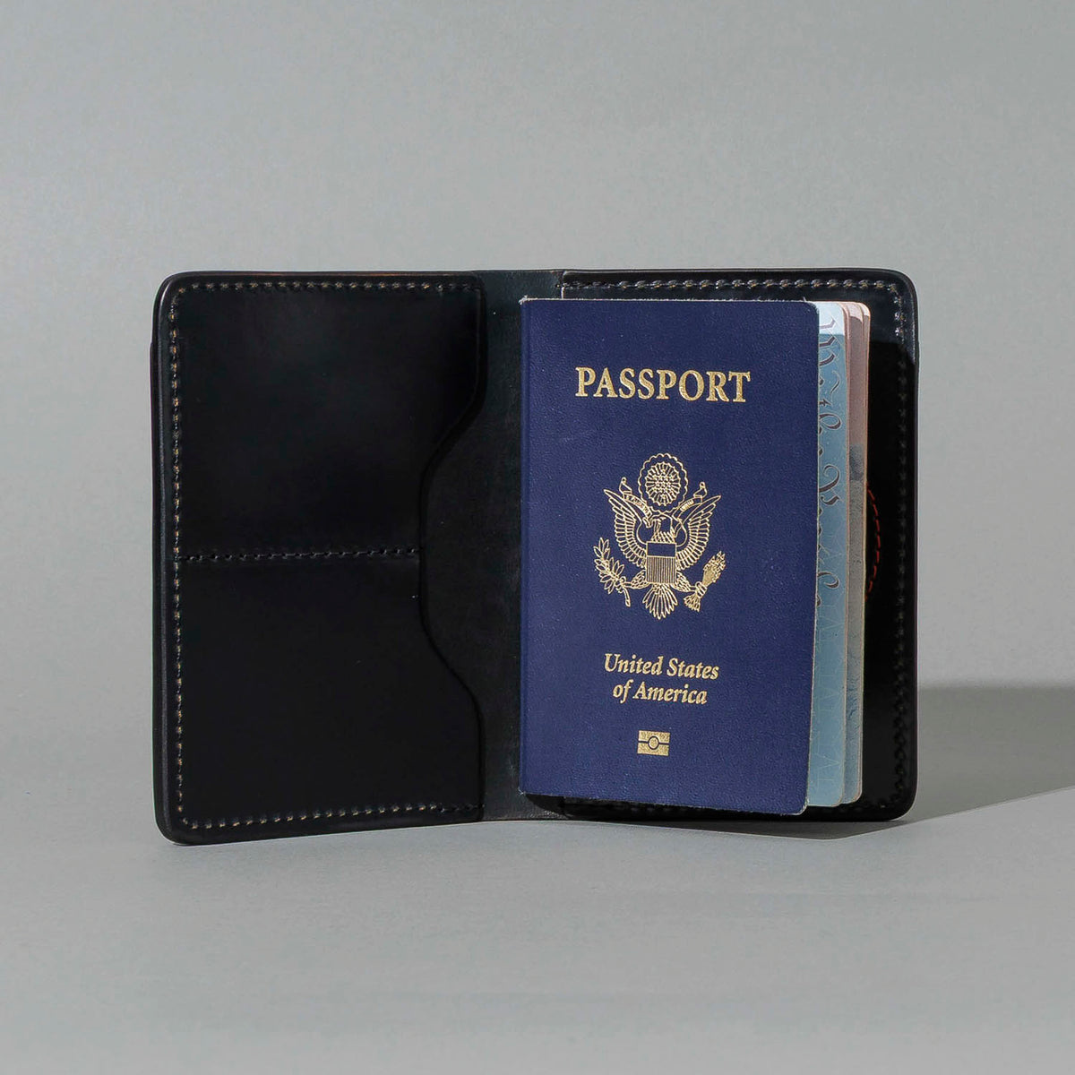 One-Off Traveler Passport Holder in Black Shell Cordovan with Red Pentagram Embroidery, open with a passport inside