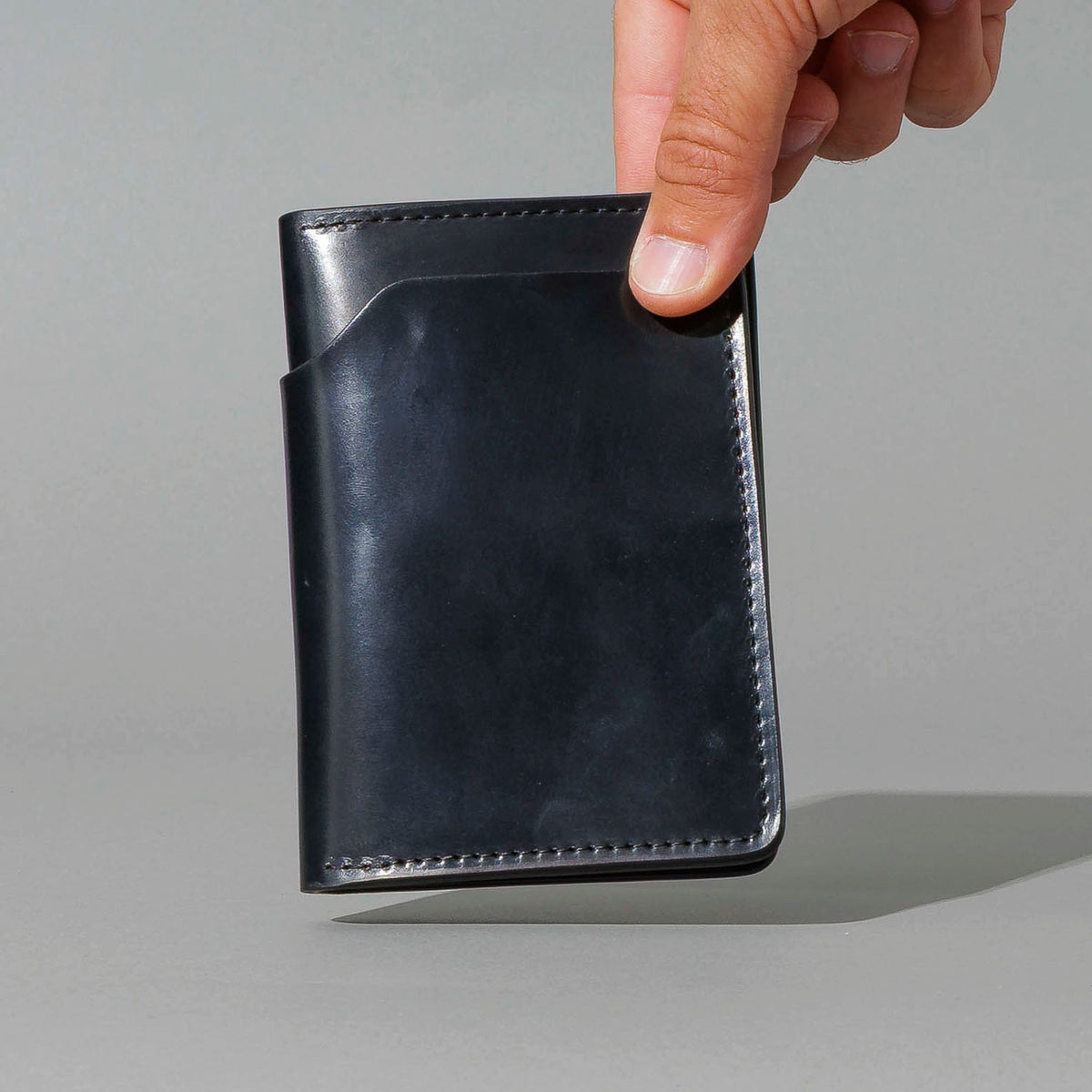 One-Off Traveler Passport Holder in Black Shell Cordovan with Red Pentagram Embroidery, held in hand, shot 1
