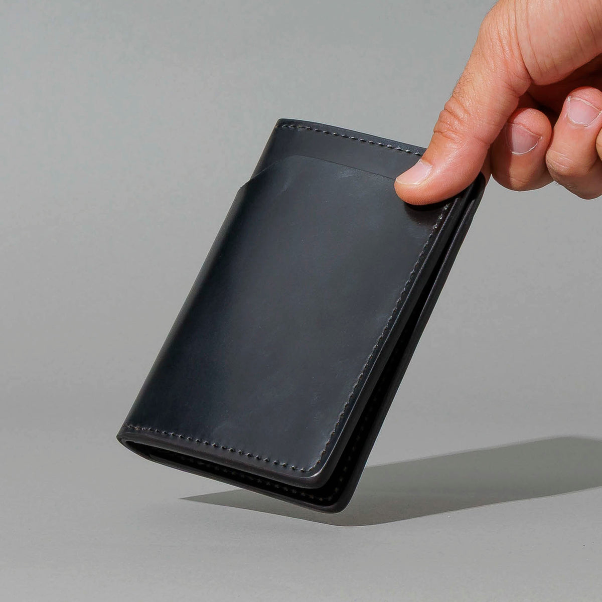 One-Off Traveler Passport Holder in Black Shell Cordovan with Red Pentagram Embroidery, held in hand, shot 3