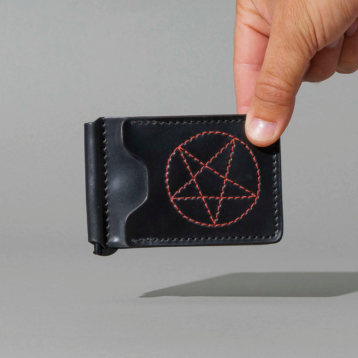 One-Off Capone Money Clip in Black Shell Cordovan with Red Pentagram Embroidery, held in hand, shot 1