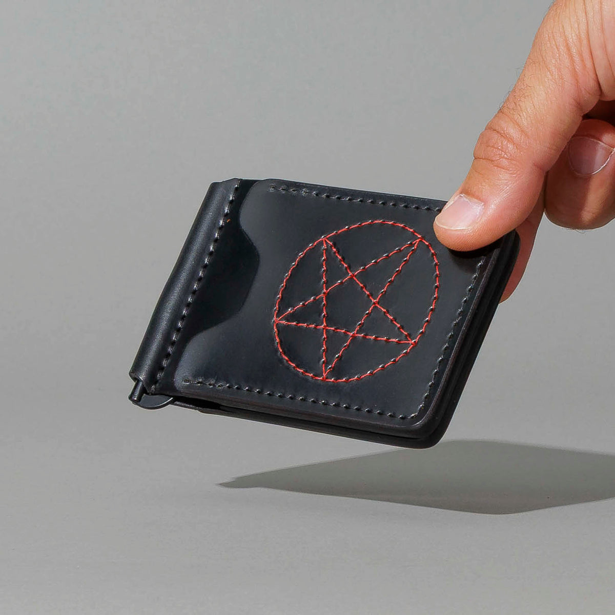 One-Off Capone Money Clip in Black Shell Cordovan with Red Pentagram Embroidery, held in hand, shot 2