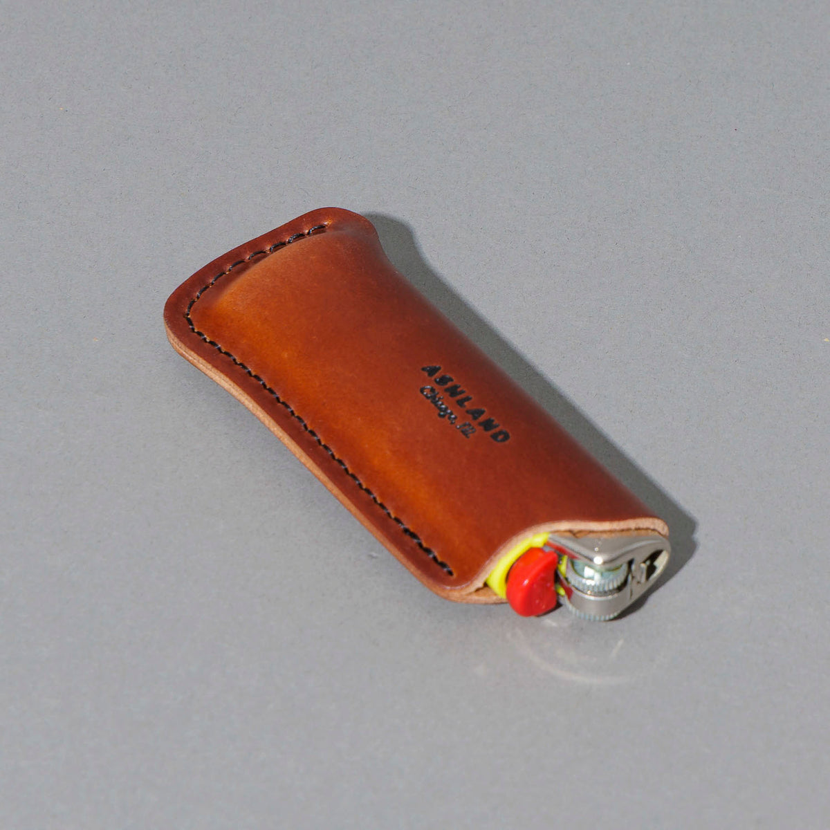 One-Off Lighter in Blood Orange Shell Cordovan, angled view lying flat