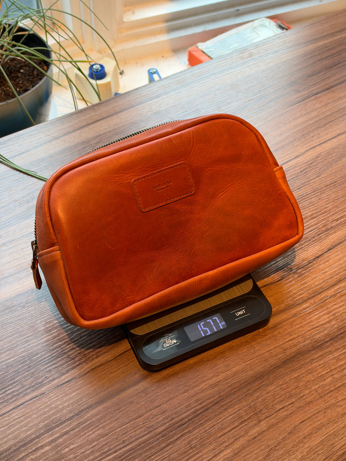 Leather sling bag in Horween® English Tan Dublin on a kitchen scale reading 15.77 oz