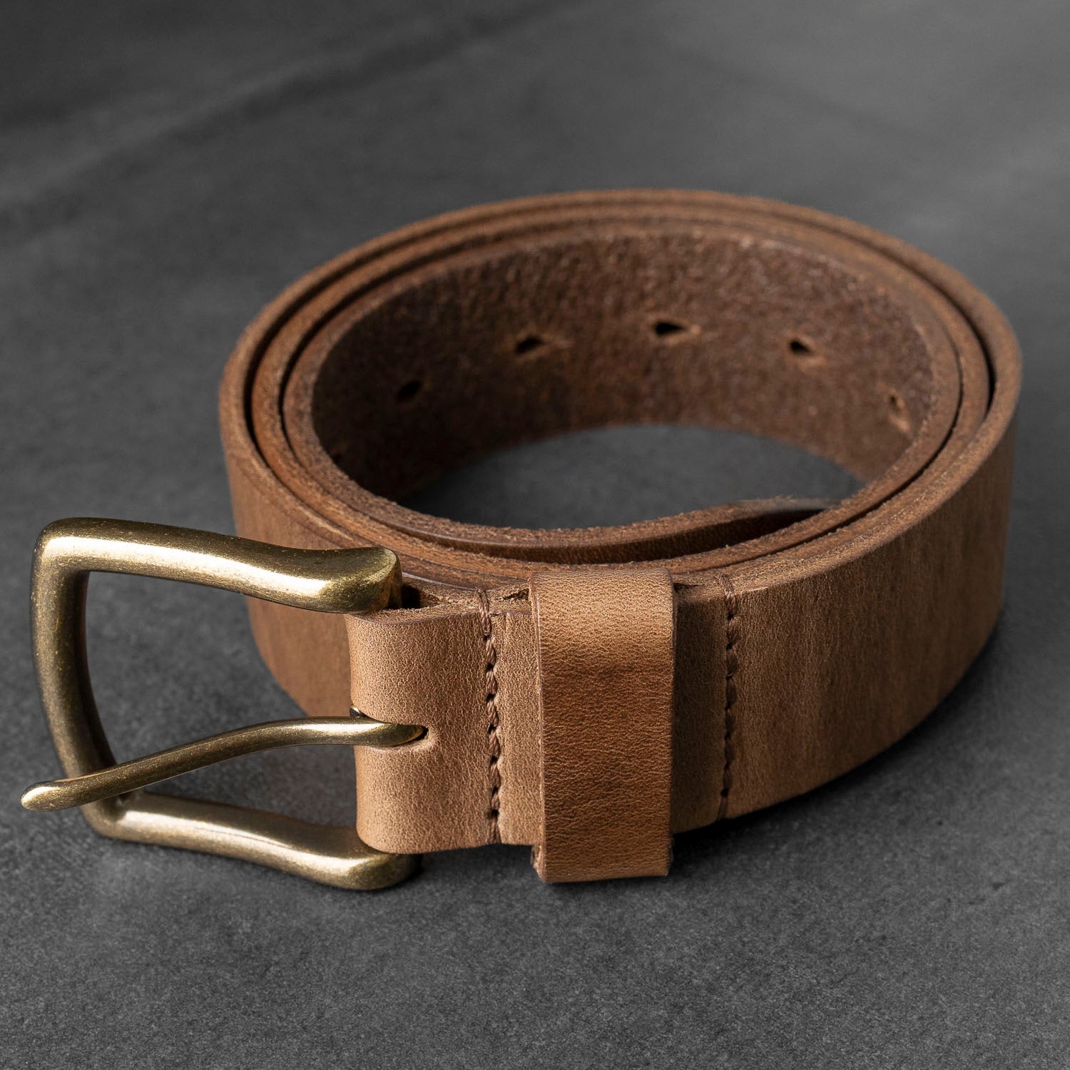 Ashland chromexcel leather belt coiled on gray background showing interior leather grain
