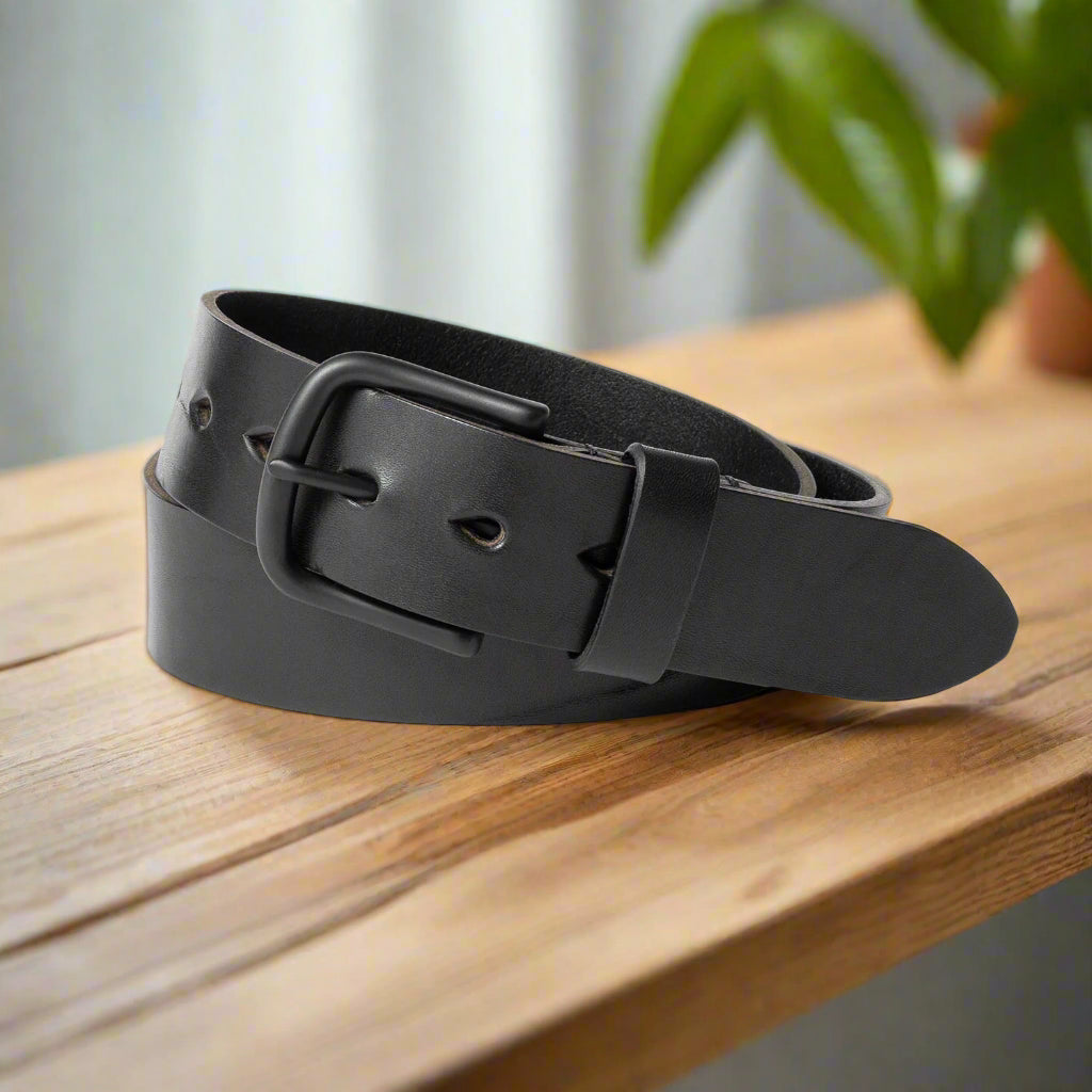 Black leather belt with a buckle on a wooden shelf