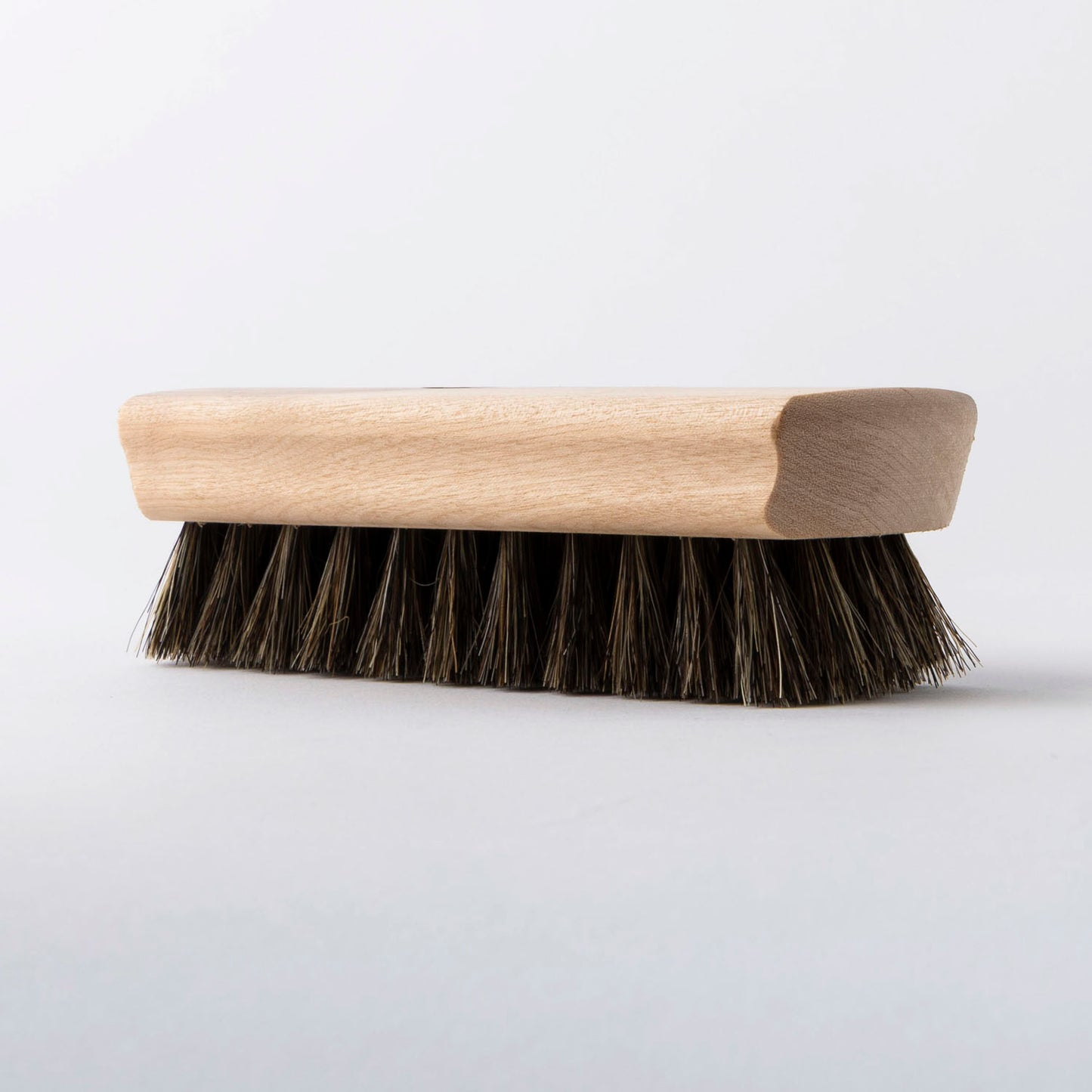 Leather cleaning brush with wooden handle and bristles on a white background