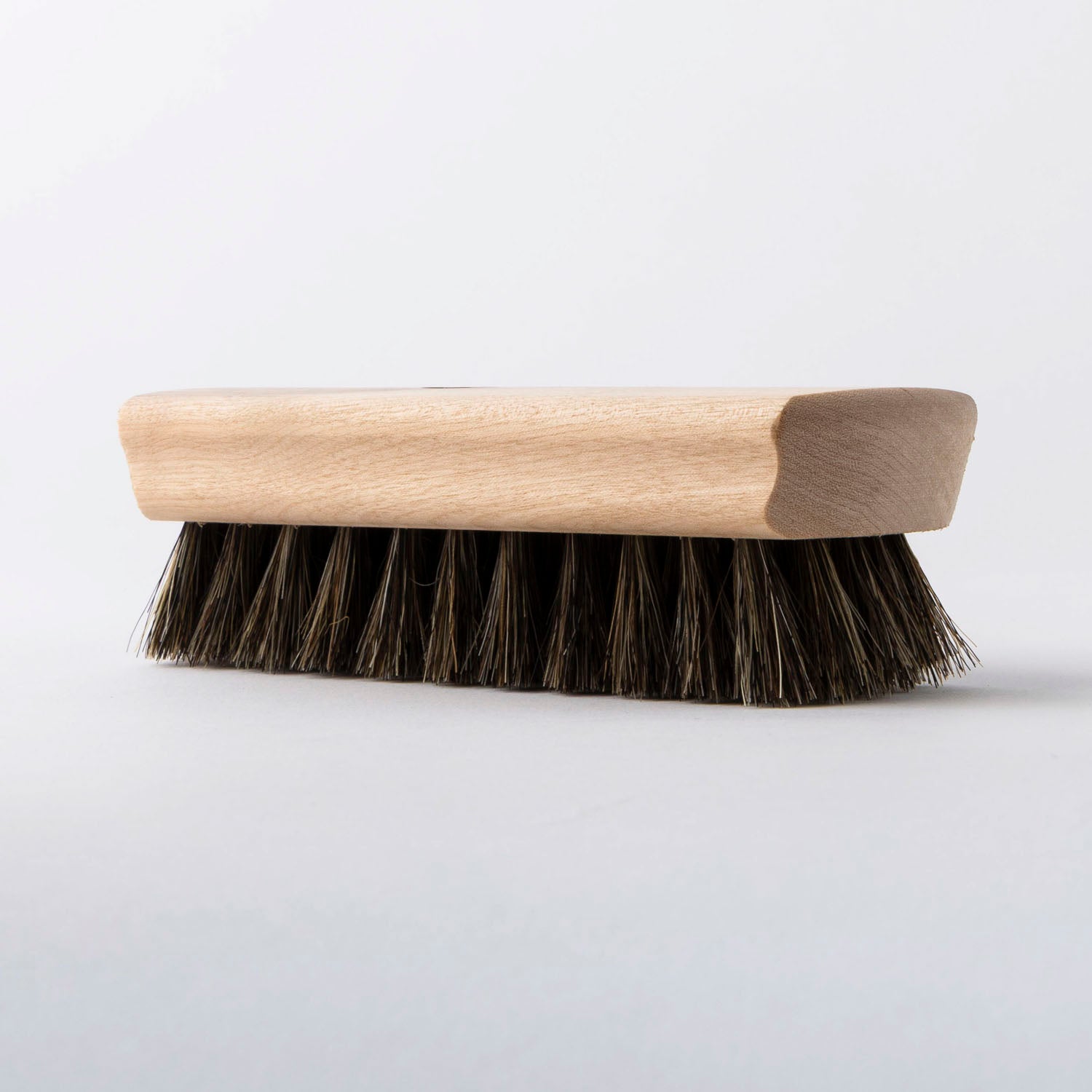 Leather cleaning brush with wooden handle and bristles on a white background