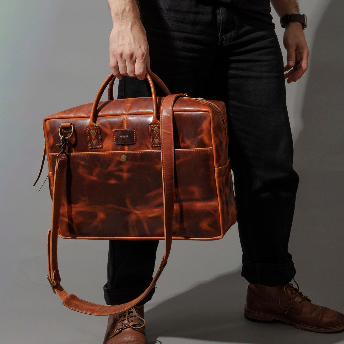 Model carrying the Ashland Leather LaSalle Briefcase by its top handle while walking