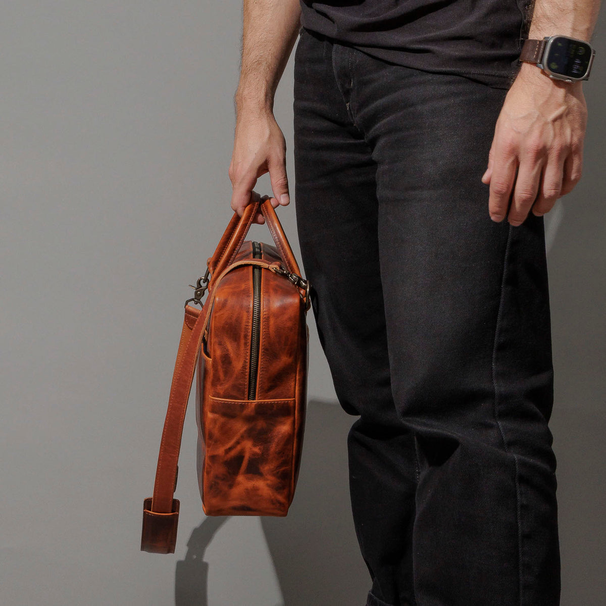 Model holding the Ashland Leather Burnt Orange Cypress LaSalle Briefcase by the top handle, standing