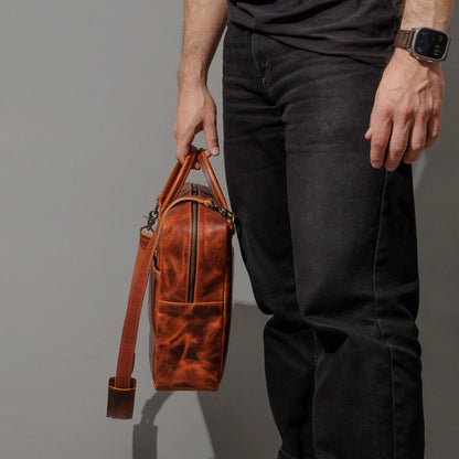 Model holding the Ashland Leather Burnt Orange Cypress LaSalle Briefcase by the top handle, standing