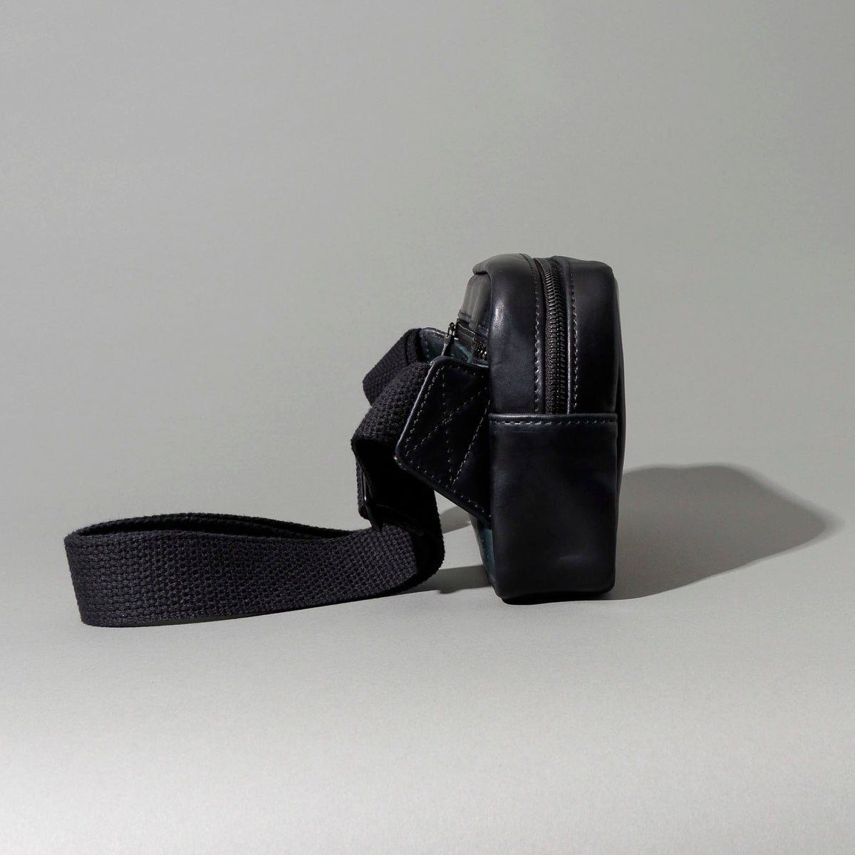 Back view of the Ashland Leather Sling Bag showing the exterior pocket and strap laid flat