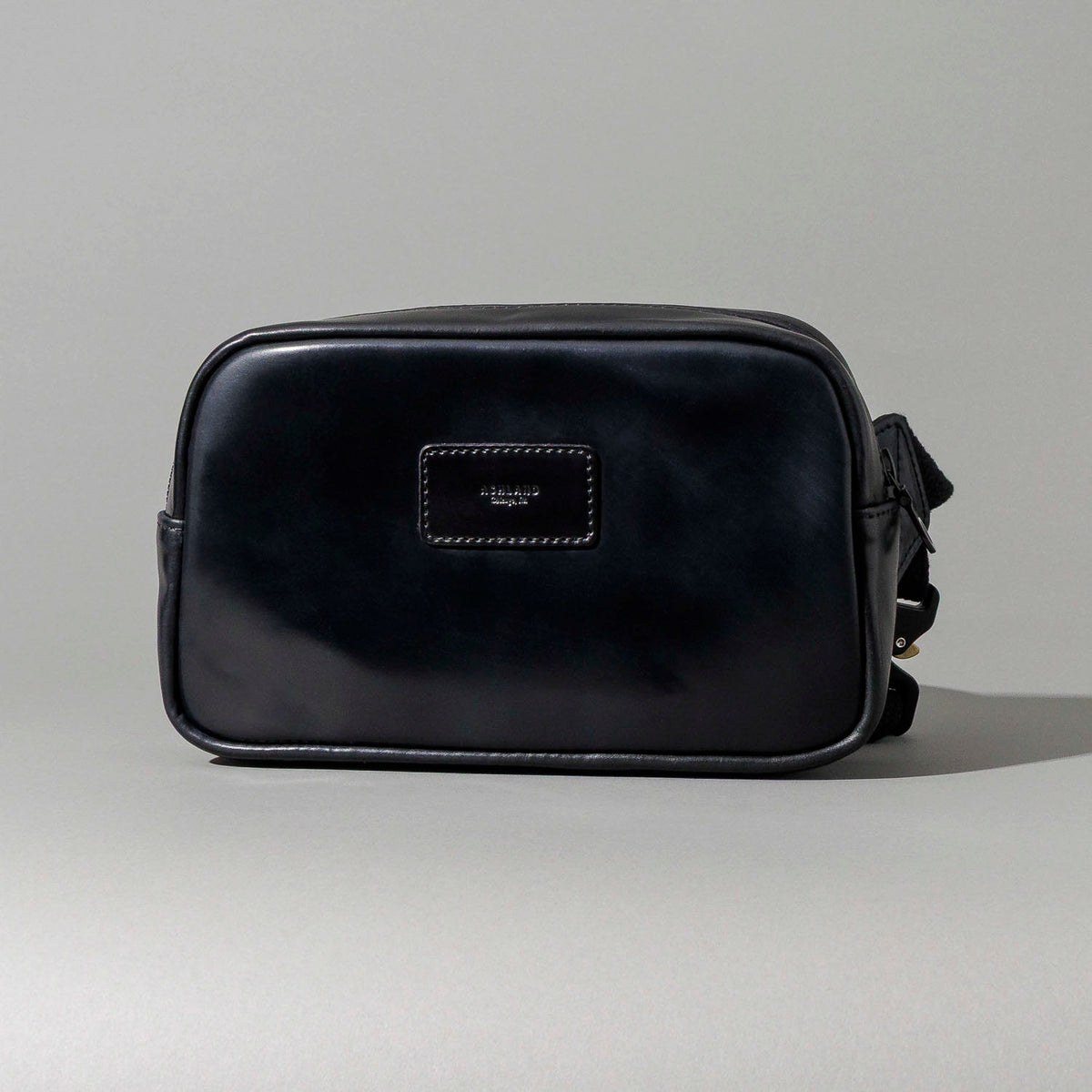 Hand opening the Ashland Leather Sling Bag to show the interior pocket organization