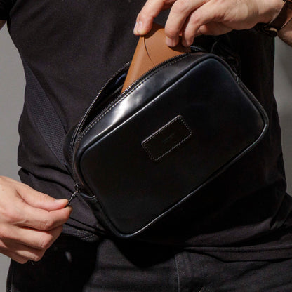 Reaching into the main compartment of the Ashland Leather Sling Bag, navy lining visible