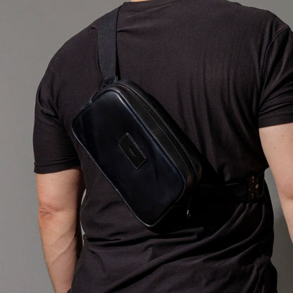 Ashland Leather black Shell Cordovan Sling Bag worn on the side, three-quarter angle