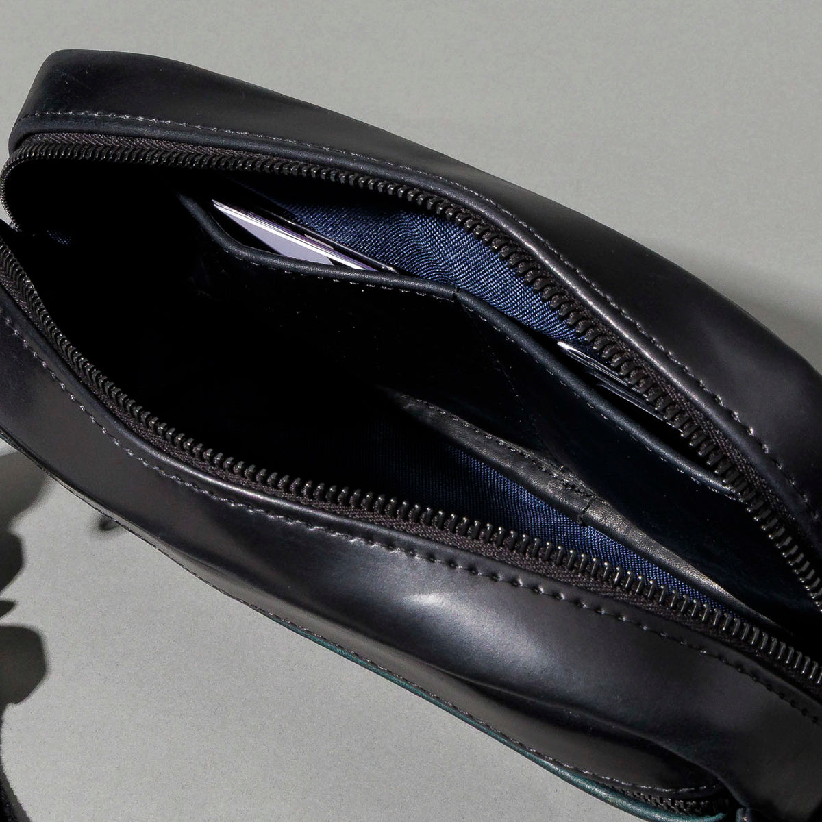 Close-up of the RiRi zipper pull and stitching on the Ashland Leather Sling Bag