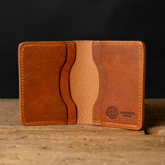 Brown leather wallet on a wooden surface with a dark background