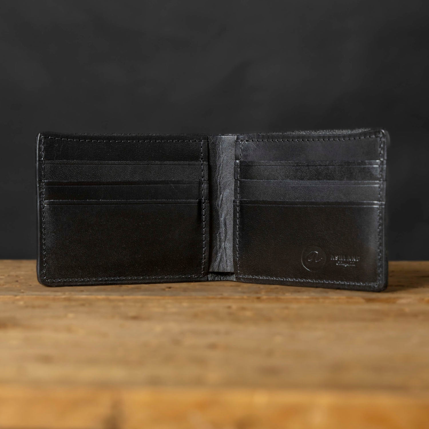 Black leather wallet open on a wooden surface with a dark background