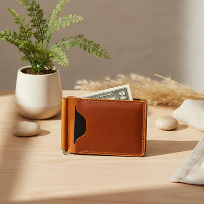 Brown leather money clip with a two dollar bill sticking out on a light wood tone table background
