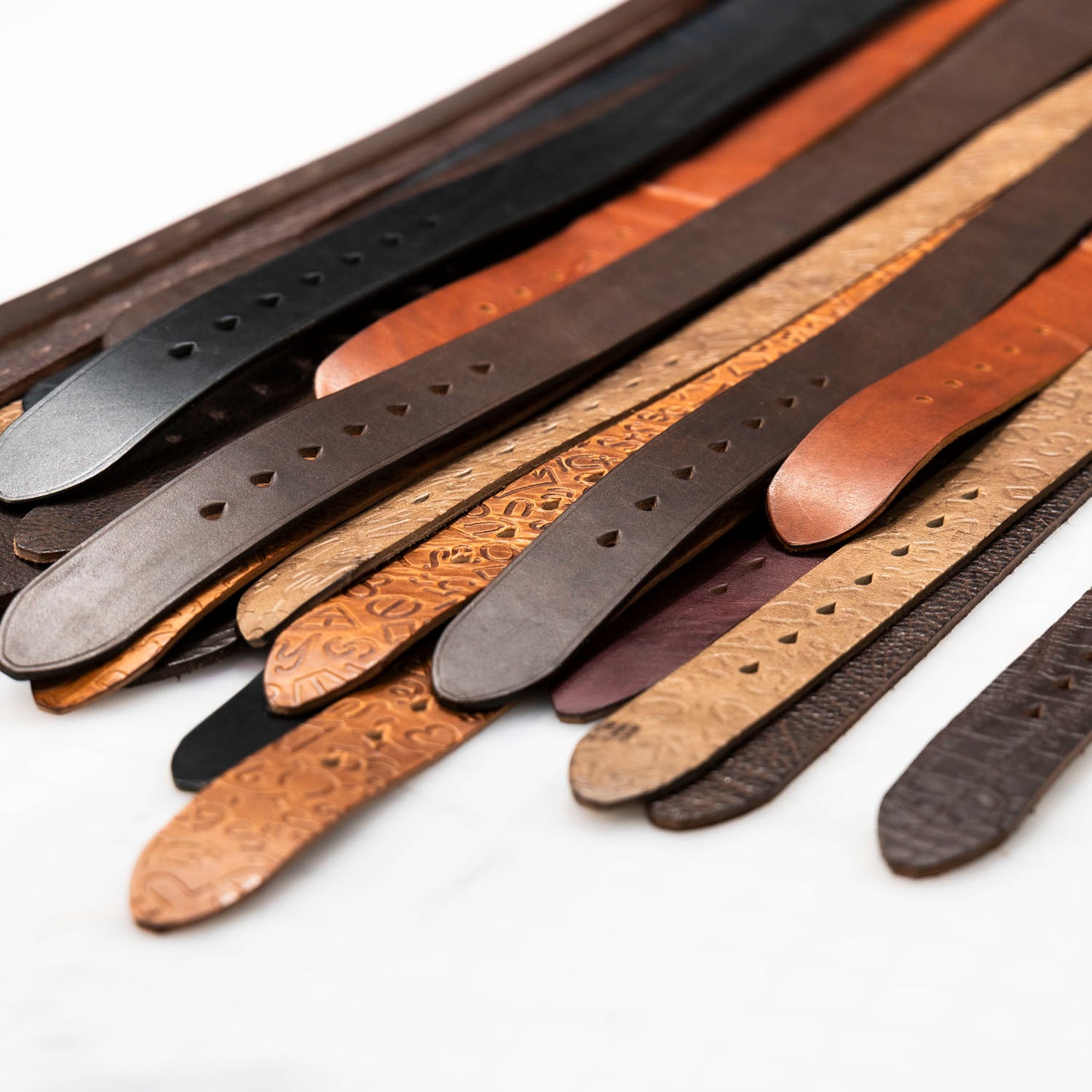 Collection of leather belts in various colors on a white background