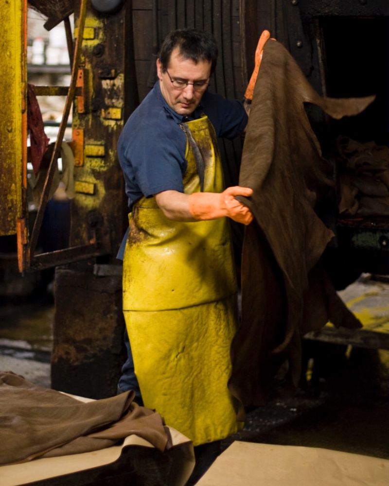 A worker in a yellow apron handling a hide at the Horween® tannery, Chicago