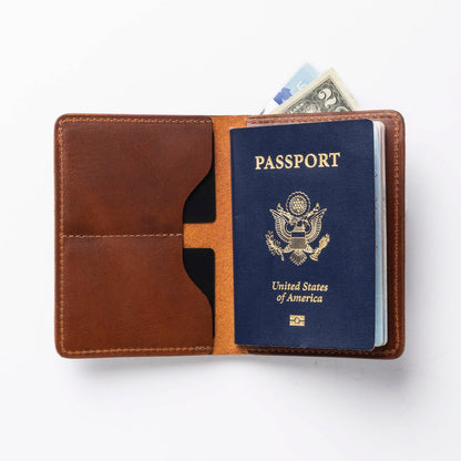 Brown leather passport holder with a U.S. passport and dollar bill on a white background