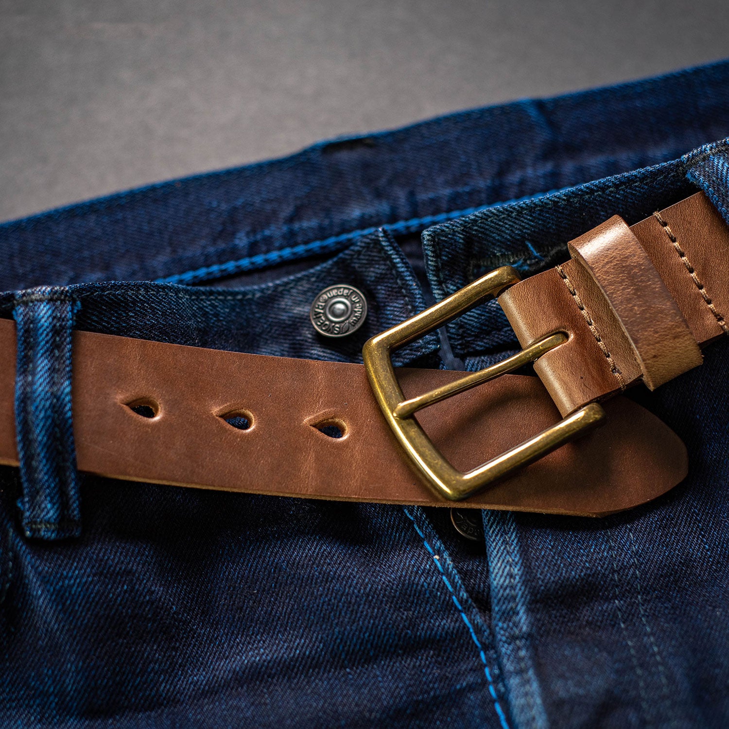 CXL natural leather men's belt shown with brass buckle visible paired with selvedge denim